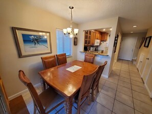 A dining room with a wooden table and chairs, a chandelier, and a framed picture on the wall. - Summerhouse 251:  Ocean View-Beach, Pool & Tennis (St. Augustine)