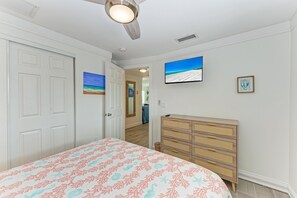 Un dormitorio con cama, cómoda y ventilador de techo.