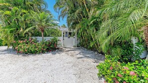A pathway leading to a gated entrance surrounded by lush greenery and flowering plants.