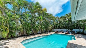 A swimming pool surrounded by palm trees and a white fence.