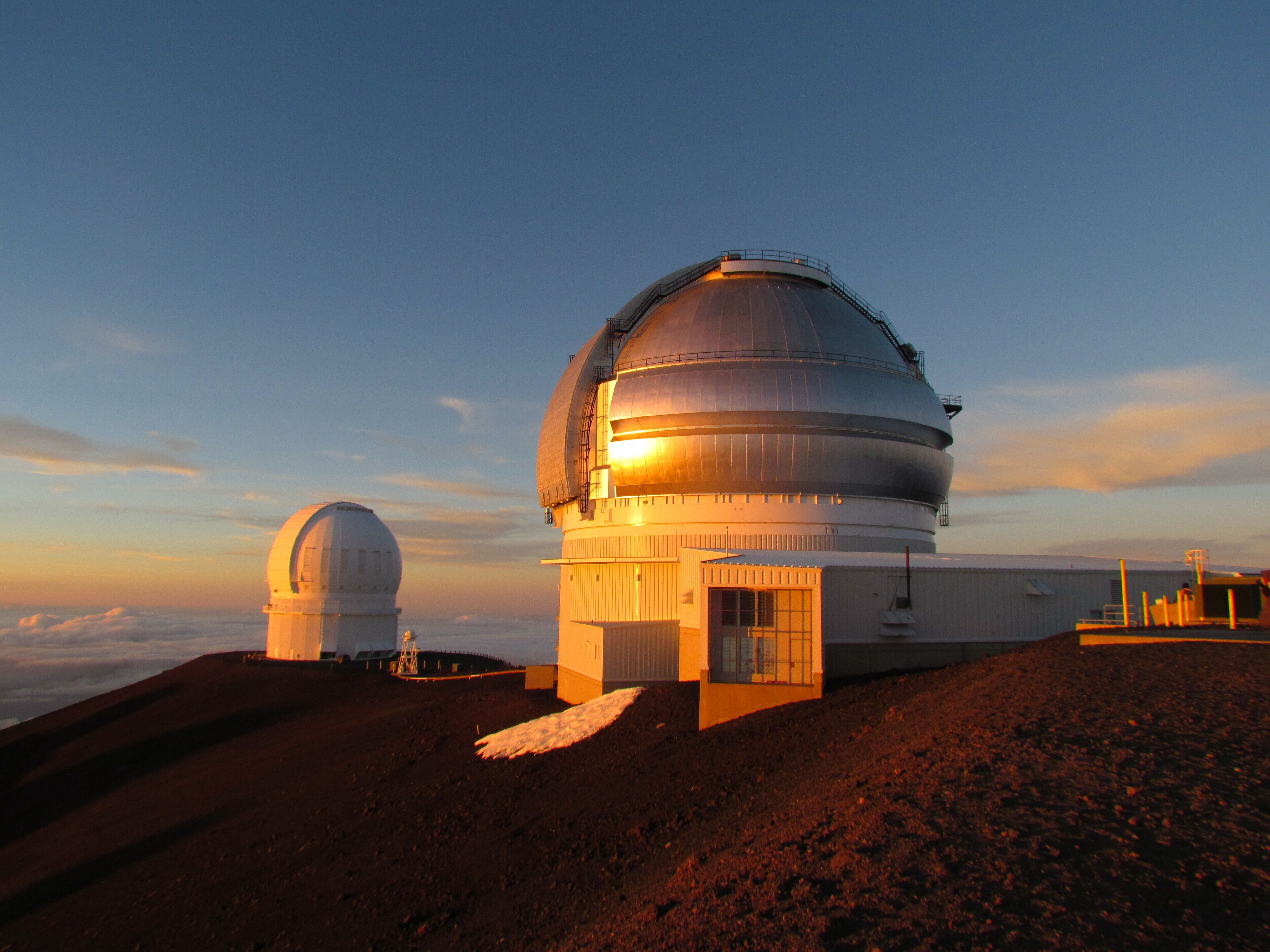 Two large observatory domes on a hill with clear skies.