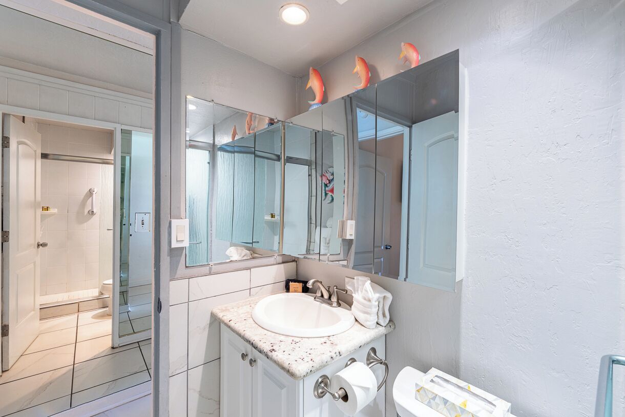 A modern bathroom with a large mirror, a sink, and a toilet.