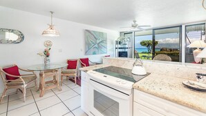 Una cucina moderna con un tavolo da pranzo in vetro, elettrodomestici bianchi e vista sull'oceano.