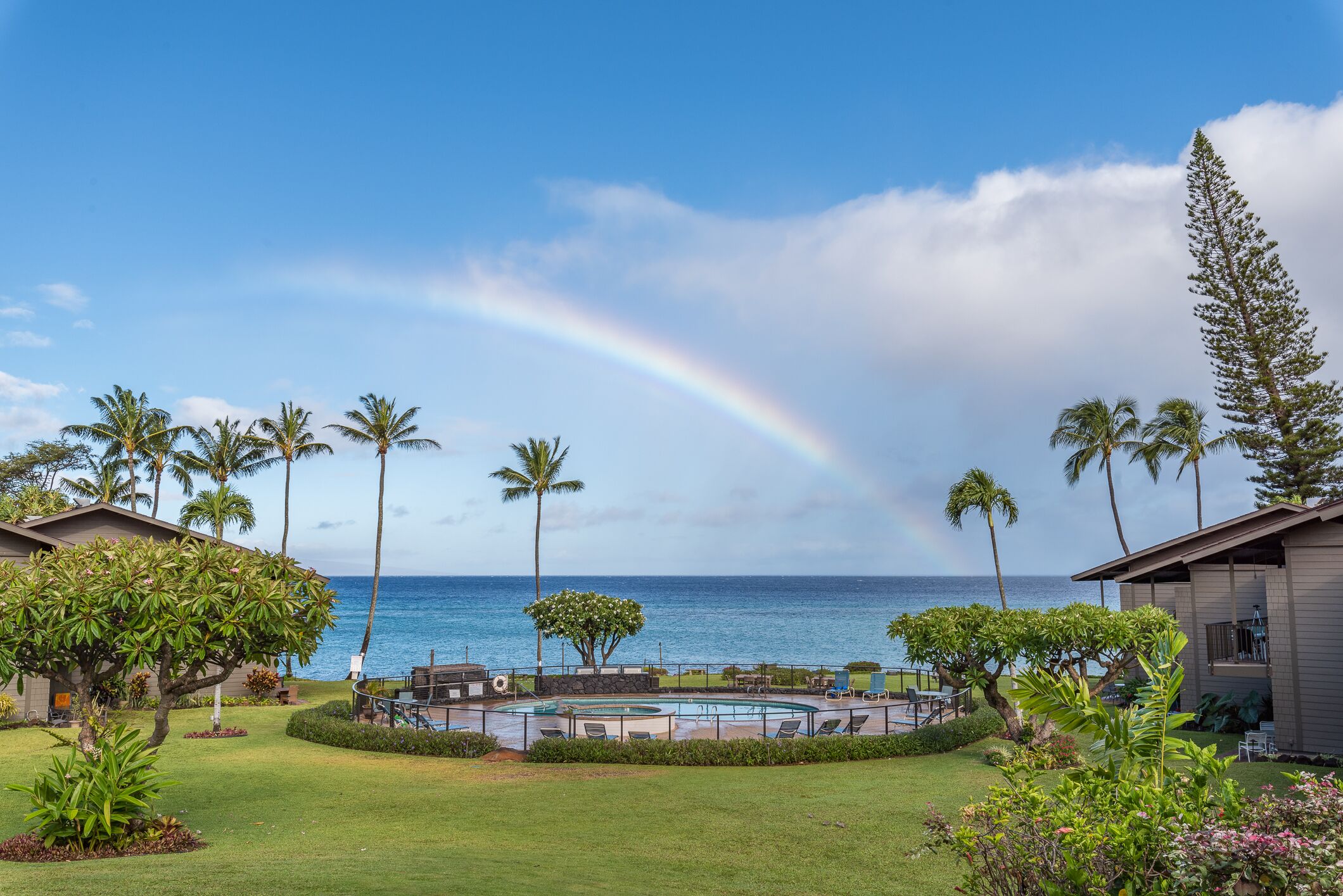 A pool area with a view of the ocean and a rainbow.