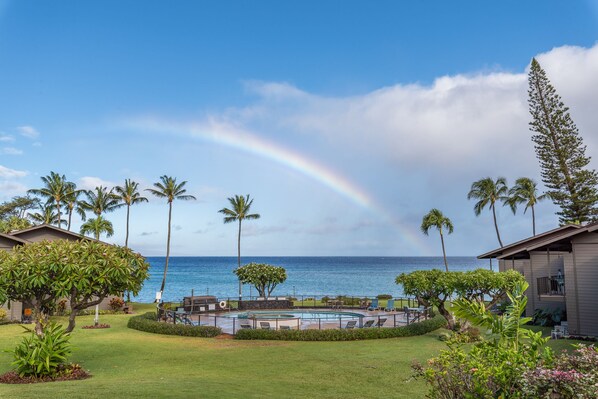 A pool area with a view of the ocean and a rainbow.