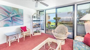 Un soggiorno spazioso con un'ampia finestra, una ventola a soffitto e vista sull'oceano.