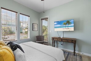 A bedroom with a bed, a desk, a chair, and a TV on the wall.