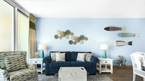 A living room with a blue sofa, patterned armchair, and a decorative fish wall art.
