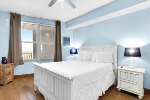 Une chambre à coucher avec un grand lit, une table de chevet, une commode et une fenêtre avec des rideaux.