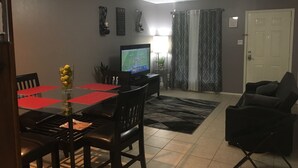 A dining area with a red table and chairs, a television, and a ceiling fan. - Private Duplex #1 - Houston Hobby/ClearLake/Galveston/Pasadena/Downtown (Houston)