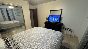 A hotel room with a bed, a dresser, a TV, and a mirror. - Private Duplex #1 - Houston Hobby/ClearLake/Galveston/Pasadena/Downtown (Houston)