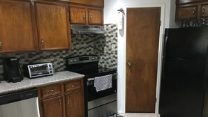 A kitchen with wooden cabinets, a toaster, a stove, and a refrigerator. - Private Duplex #1 - Houston Hobby/ClearLake/Galveston/Pasadena/Downtown (Houston)