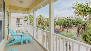 A balcony with a white railing, a blue chair, and a table. - Alabama Sunrise- 3BR/3BA crescent beach home - Pet Friendly (Gulf Shores)