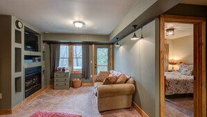 A cozy room with a fireplace, a sofa, a bed, and a small table.