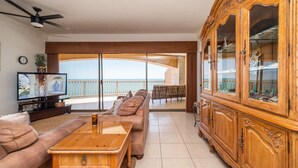 A living room with a sofa, coffee table, TV, and a wooden cabinet.