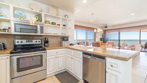 A modern kitchen with stainless steel appliances, white cabinetry, and a large island.