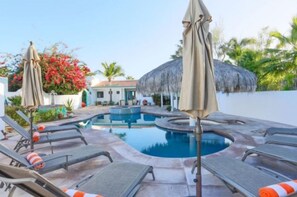 Relax by the serene pool surrounded by lounge chairs and umbrellas.