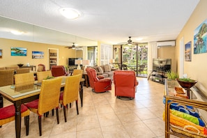 A spacious living area with a dining table, chairs, sofas, and a TV.