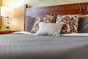 Una cama bien hecha con almohadas estampadas y un cabecero de madera.