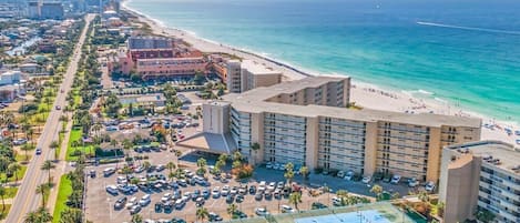 Un hotel sul lungomare con parcheggio e una grande costruzione su più piani.