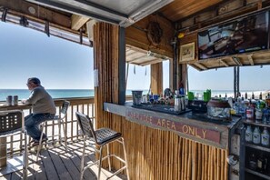 A bar area with a view of the ocean, a service counter, and a television screen.