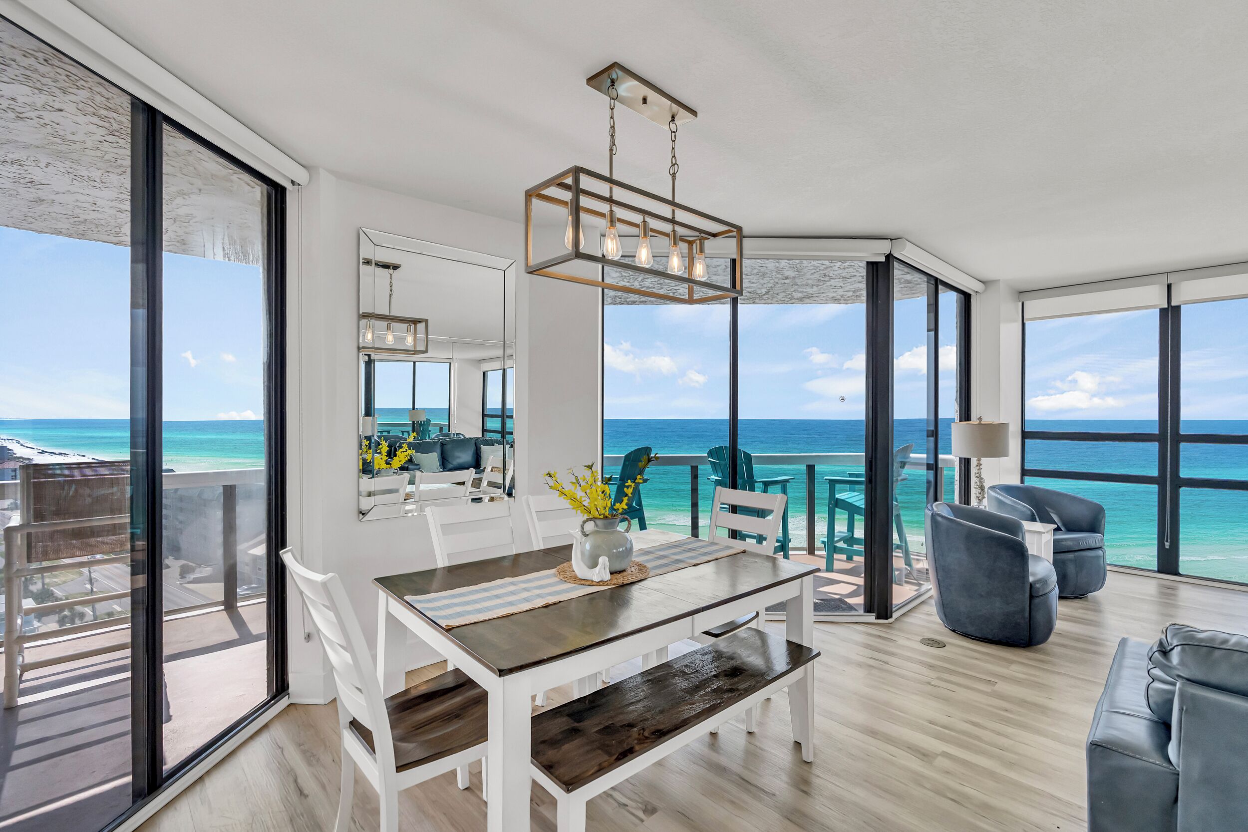 A modern interior with a dining area, a seating area with a view of the ocean, and a large window.