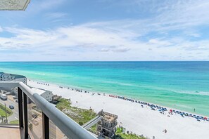 A beach with clear turquoise waters, a white sandy shore, and a view of a building with a balcony overlooking the beach. - 2 Free Beach Svc=4 Chairs/2 Umbrellas! Free Beach Bonfires M/F nts! AWESOME View (Miramar Beach)