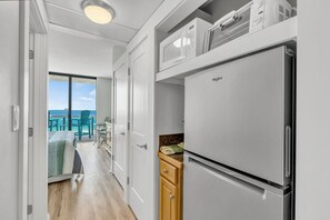 Eine moderne Küche mit integriertem Kühlschrank, Holzausstattung und Meerblick durch eine Schiebetür.