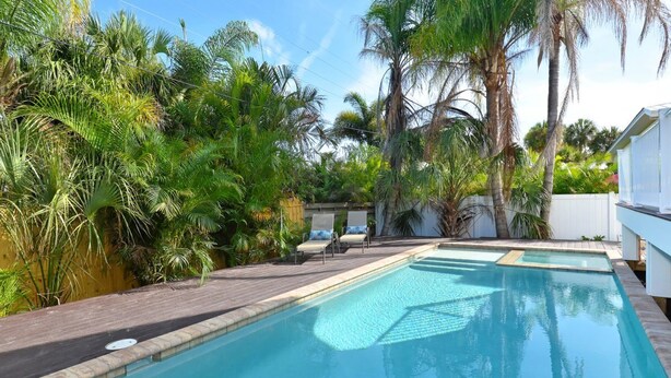 A swimming pool surrounded by lush greenery and palm trees.