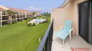 Ein Balkon mit Liegestuhl, Pool und einem Gebäude mit mehreren Balkonen.