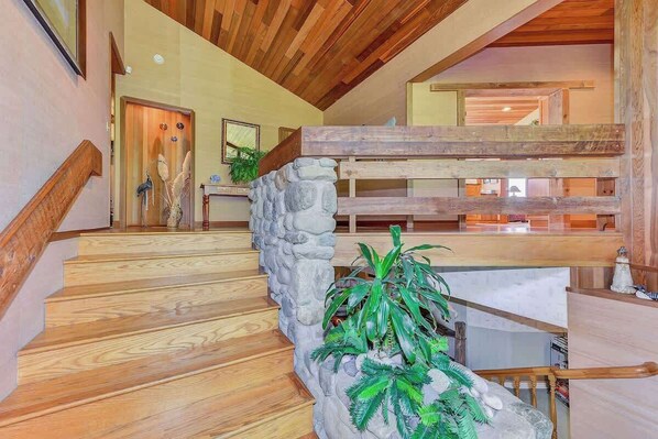 A wooden staircase with a stone wall and a plant.