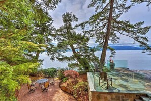 A patio with a round table and chairs, overlooking a body of water and mountains. - Oceanside Lodge Saanich Inlet (North Saanich)