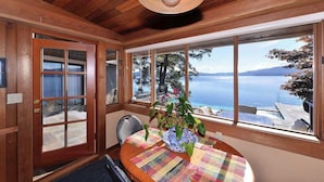 Un intérieur en bois avec de grandes fenêtres donnant sur une étendue d’eau et offrant une vue sur un bateau.