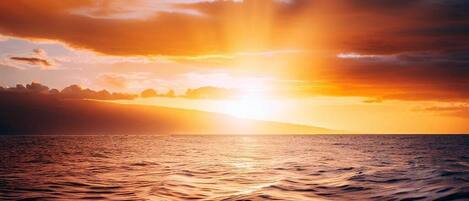 Una puesta de sol sobre un mar tranquilo con horizonte despejado.
