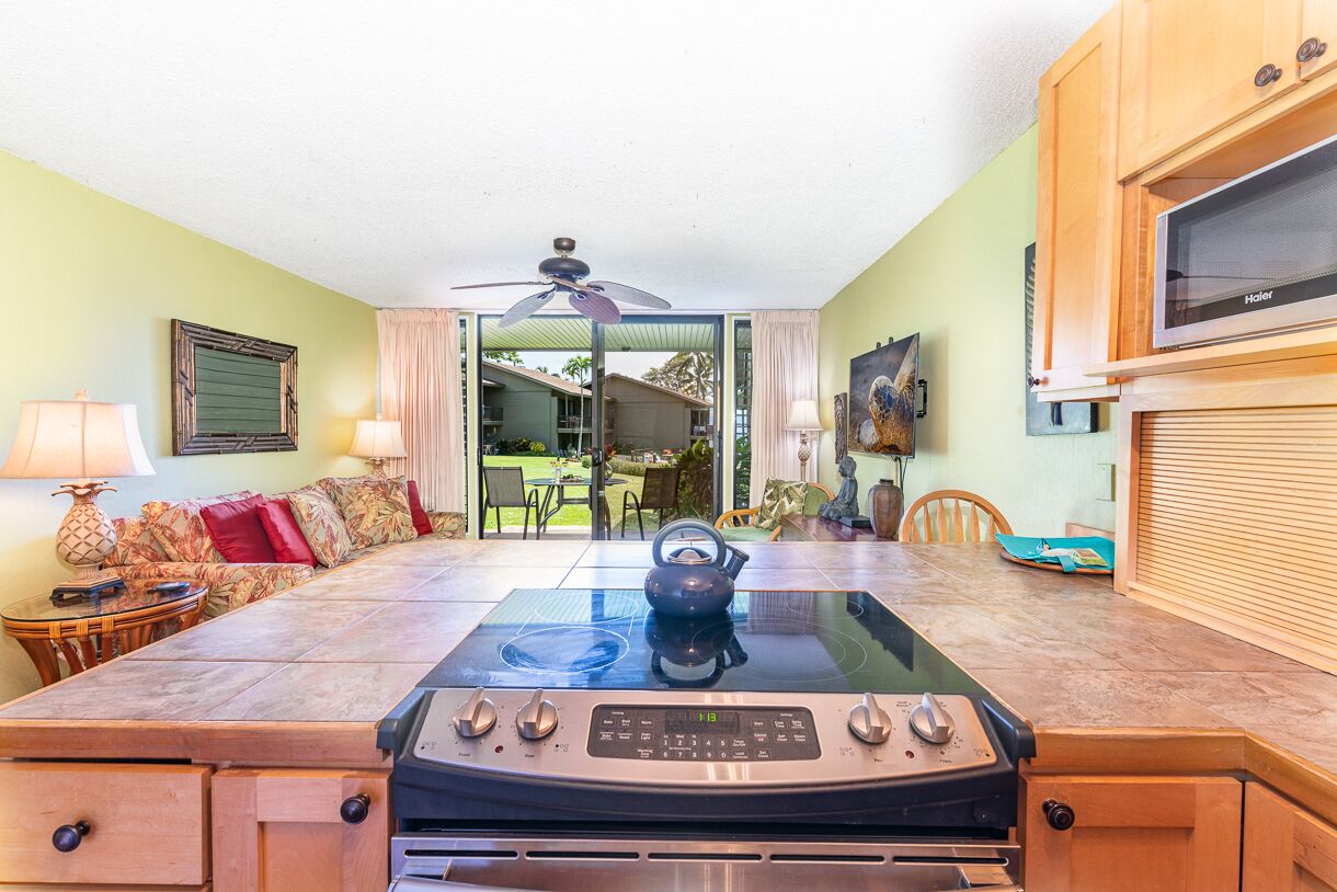 A kitchen with a stove, a ceiling fan, and a dining area with a table and chairs.