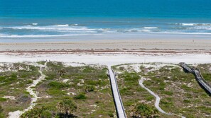 A beach with a wooden boardwalk leading to the shore, sandy dunes, and ocean. - Spacious Oceanfront Pool Home! (Saint Augustine)