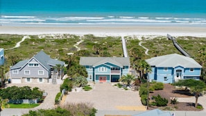 En fastighet vid stranden med tre hus, en asfalterad uppfart och en strandpromenad som leder ner till stranden.