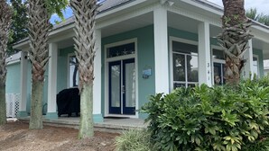 A two-story building with a covered porch, palm trees, and a well-maintained lawn. - Relaxing beach retreat steps away to beach, pools, hot tub tennis/pickleball! (Destin)