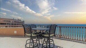 A terrace with a table and chairs overlooking the sea.