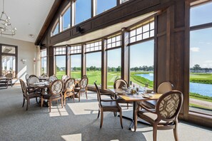 A dining area with large windows overlooking a golf course and water. - 22096 S Preservation Drive (Millsboro)