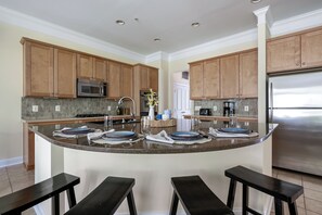 A modern kitchen with wooden cabinets, stainless steel appliances, and a central island with bar stools.