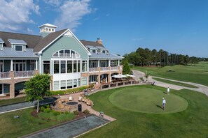 A large building with a covered patio and a golf course in the background.