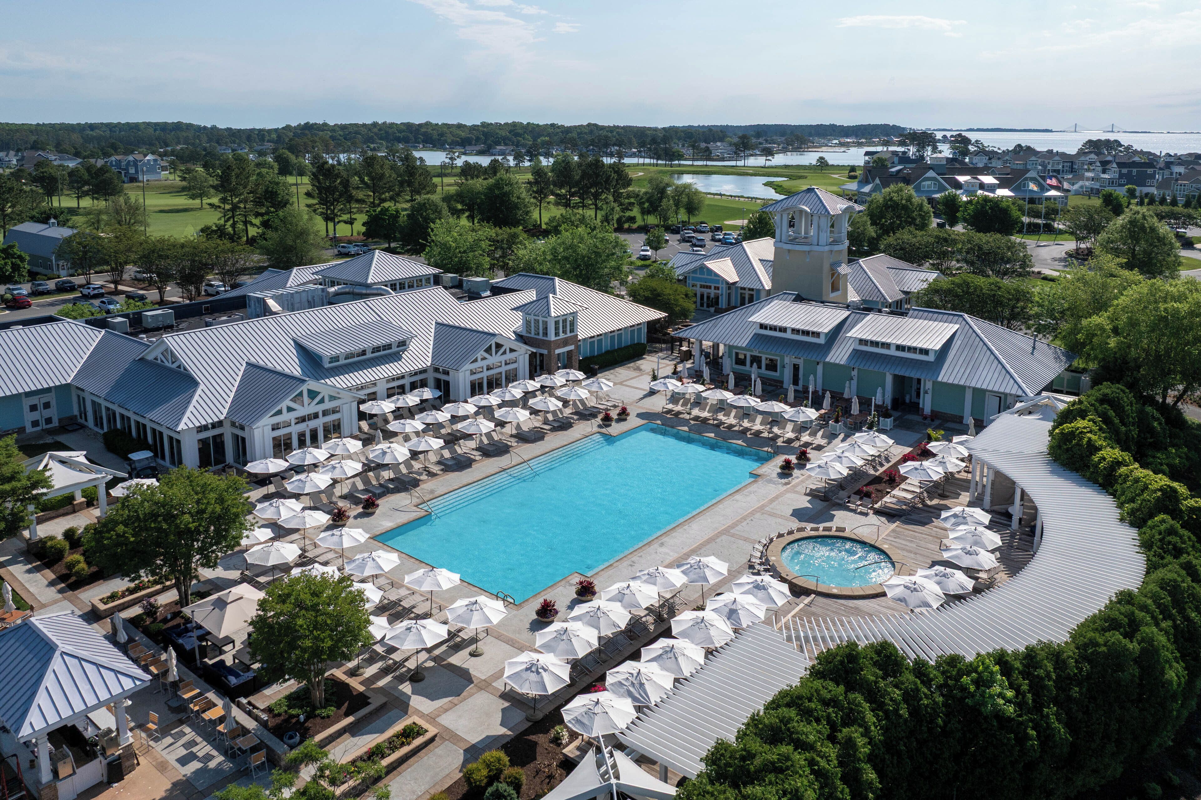 A resort with a large swimming pool, outdoor seating, and a view of the surrounding landscape.