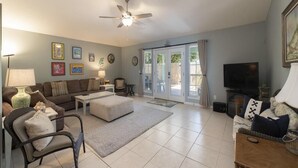 A spacious living room with a ceiling fan, a sofa set, a television, and a dining area. - Modern Beach Retreat ~ Close to the Beach! (Saint Augustine)