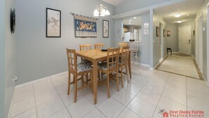 A dining area with a wooden table and chairs, a chandelier, and framed artwork on the walls. - Modern Beach Retreat ~ Close to the Beach! (Saint Augustine)