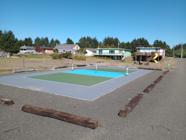 Un court de tennis avec un filet, entouré d’une zone recouverte de gravier.