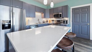 A modern kitchen with grey cabinets, stainless steel appliances, a white marble island, and pendant lighting. - PICKLEBALL, NEW HOT TUB, Ocean View, Playset (SV2) (Long Beach)