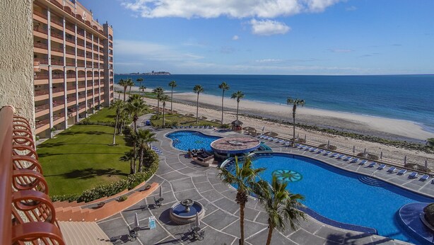 A hotel with a pool area, including a hot tub and lounge chairs, overlooking a beach and ocean. - Sonoran Sun W-510 Sunny Charmed Life Adorable Oceanfront Condo (Puerto Penasco)