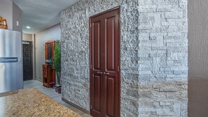 A hallway with a stone wall, a wooden door, a refrigerator, and a plant. - Sonoran Sun W-510 Sunny Charmed Life Adorable Oceanfront Condo (Puerto Penasco)