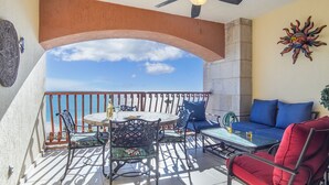 A balcony with a table and chairs, a sofa, and a decorative sun sculpture. - Sonoran Sun W-510 Sunny Charmed Life Adorable Oceanfront Condo (Puerto Penasco)